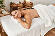 © Krakenimages.com - Young beautiful hispanic woman lying on table having hot stones massage at beauty salon