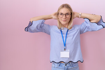 Canvas Print - Young caucasian business woman wearing id card relaxing and stretching, arms and hands behind head and neck smiling happy