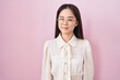 Young chinese woman standing over pink background winking looking at the camera with sexy expression, cheerful and happy face.