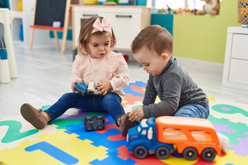 Adorable boy and girl playing with cars toy sitting on floor at kindergarten