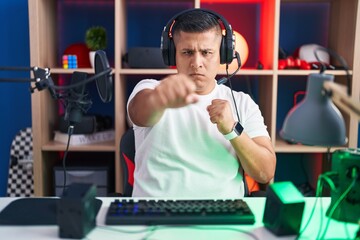 Poster - Young hispanic man playing video games punching fist to fight, aggressive and angry attack, threat and violence