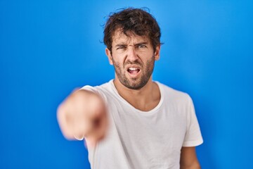 Poster - Hispanic young man standing over blue background pointing displeased and frustrated to the camera, angry and furious with you