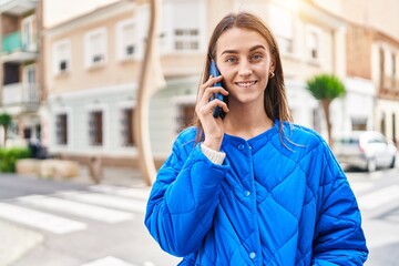 Wall Mural - Young caucasian woman smiling confident talking on the smartphone at street