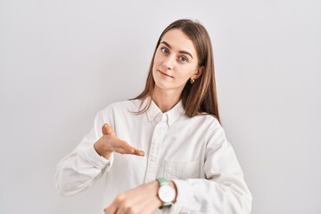 Sticker - Young caucasian woman standing over isolated background in hurry pointing to watch time, impatience, upset and angry for deadline delay