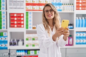 Sticker - Young woman pharmacist smiling confident using smartphone at pharmacy