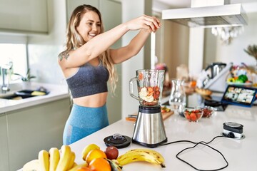 Canvas Print - Young woman smiling confident pouring strawberries on blender at kitchen