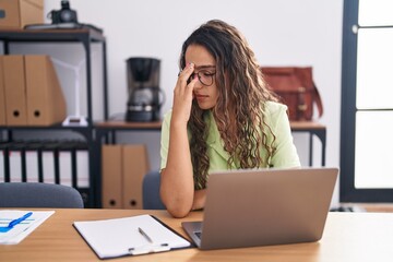 Wall Mural - Young hispanic woman working at the office wearing glasses tired rubbing nose and eyes feeling fatigue and headache. stress and frustration concept.