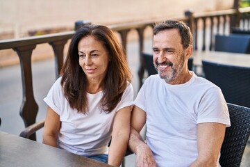 Poster - Middle age man and woman couple sitting on table at coffee shop terrace