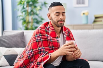 Poster - African american man drinking tea sitting on sofa at home