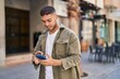 © Krakenimages.com - Young hispanic man smiling confident using smartphone at street