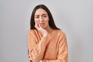 Poster - Young brunette woman standing over white background thinking looking tired and bored with depression problems with crossed arms.