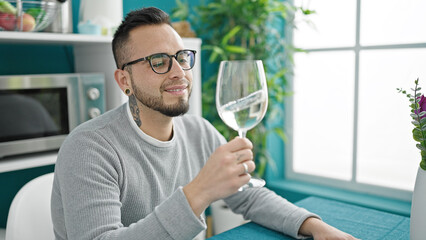 Wall Mural - Hispanic man drinking glass of wine sitting on table at dinning room