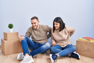 Poster - Young couple moving to a new home suffering of backache, touching back with hand, muscular pain