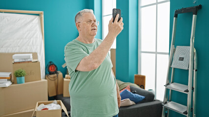 Canvas Print - Middle age grey-haired man having video call at new home