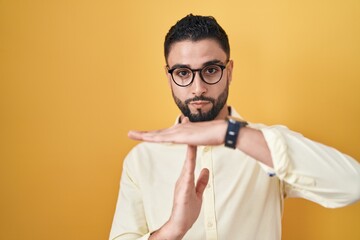 Sticker - Hispanic young man wearing business clothes and glasses doing time out gesture with hands, frustrated and serious face