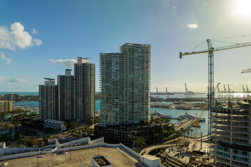 Tower lifting cranes at high residential apartment building construction site. Real estate development in Miami urban area