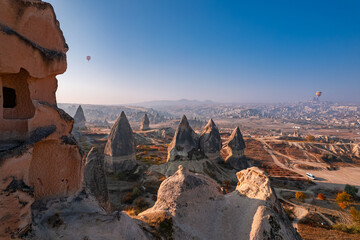 Wall Mural - Closeup ancient Goreme cave in big stone, hot air balloons fly over deep canyons, valleys Cappadocia National Park with sunlight, Turkey Travel