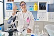 © Krakenimages.com - Hispanic girl with down syndrome working at scientist laboratory showing and pointing up with fingers number five while smiling confident and happy.