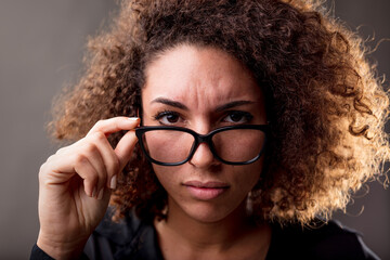 close up portrait of a very skeptical curly haired woman staring at your eyes straight