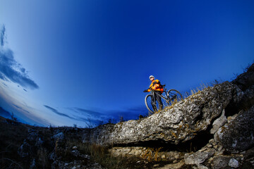 Sticker - Mountain biker in action across rocks against blue sky concept for healthy lifestyle, exercise and extreme sports