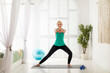 © Prostock-studio - Happy senior lady doing lunges exercise while training at home
