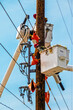 © Susan Vineyard  - Two line workers electricians in buckets high in air repairing an electric pole after storm