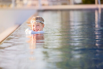 Poster - smiling cheerful boy with goggles enjoying swimming at the resort pool