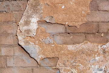 Closeup of a brick wall with chipped plaster.