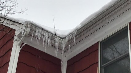 Wall Mural - close view of icicles hanging from house roof gutter after the snow storm