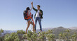 Young delightful couple giving high five to each other while standing on plat of mountain in summer.