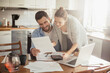 © Geber86 - Young happy couple going over their bills at home