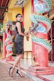 Fototapeta Młodzieżowe - A young Asian woman wearing a black dress is taking a photo at the vihara