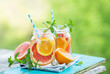 Grapefruit and orange water in glass jars in the open air. Concept for healthy eating and nutrition. Copy space.