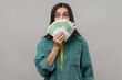 Amazed happy woman with dark hair hiding face behind fan of euro banknotes, interest-free cash withdrawal, wearing casual style jacket. Indoor studio shot isolated on gray background.