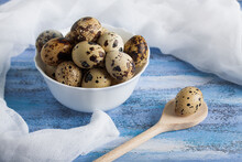 Quail Eggs In White Bowl Wooden Spoon And Gauze On Blue Wooden  Background. Easter, Front View, Horizontal Orientation.