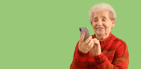 Canvas Print - Senior woman using mobile phone on green background with space for text