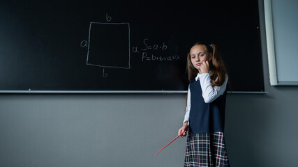 Wall Mural - The schoolgirl answers at the blackboard. Caucasian girl trying to remember the formula.