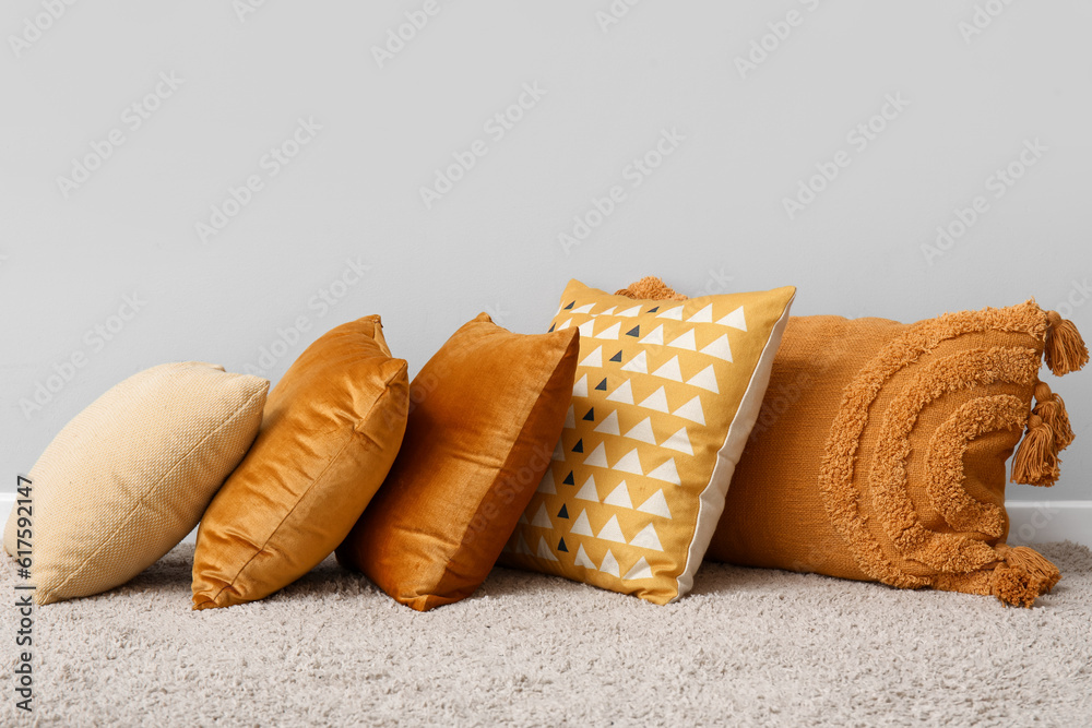 Stylish pillows on carpet near light wall in room