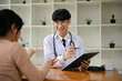 © bongkarn - A professional Asian male doctor examining a female patient in the examination room