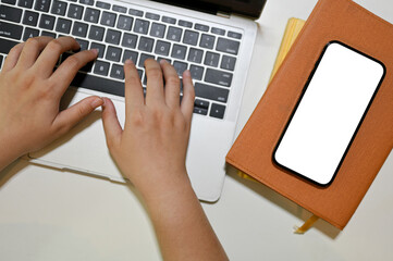 Wall Mural - Top view of a modern workspace with a female's hands typing on a laptop keyboard