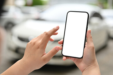 A female holding a smartphone mockup over a blurred background of a parking lot.