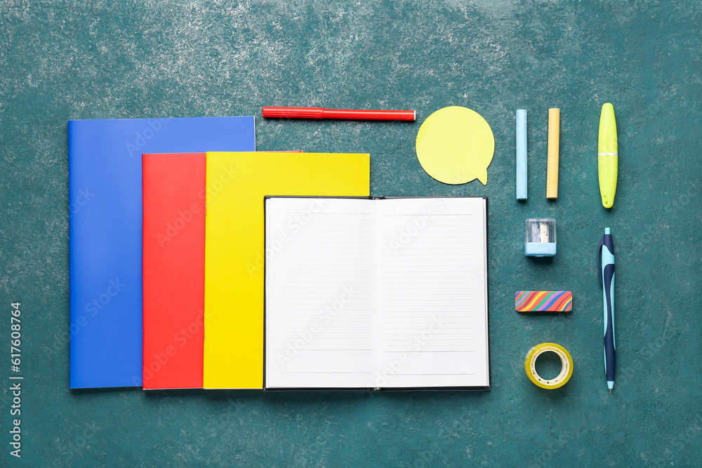 Notebooks with different school stationery on grunge turquoise background