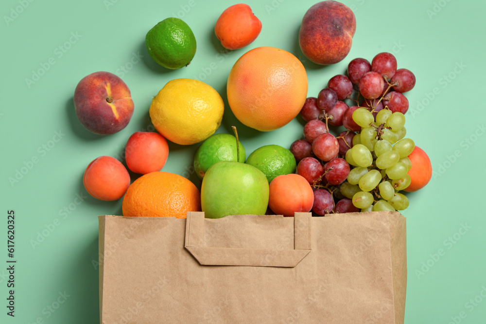 Paper bag with fresh fruits on turquoise background