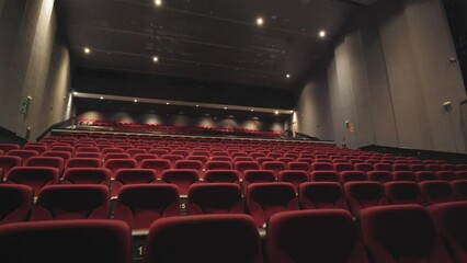 Wall Mural - Slow dolly shot along rows of red cinema seats with bright lights