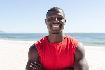 Portrait of happy african american man looking at camera and smiling on sunny beach