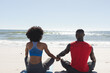 © wavebreak3 - Rear view of fit african american couple practicing yoga meditation and holding hands on sunny beach