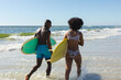 © wavebreak3 - Happy, fit african american couple carrying surfboards walking on sunny beach by the sea