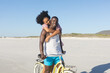 © wavebreak3 - Happy african american couple embracing riding bike on sunny beach