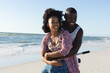 © wavebreak3 - Happy african american couple embracing riding bike on sunny beach by the sea