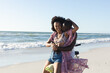 © wavebreak3 - Happy african american couple embracing riding bike on sunny beach by the sea